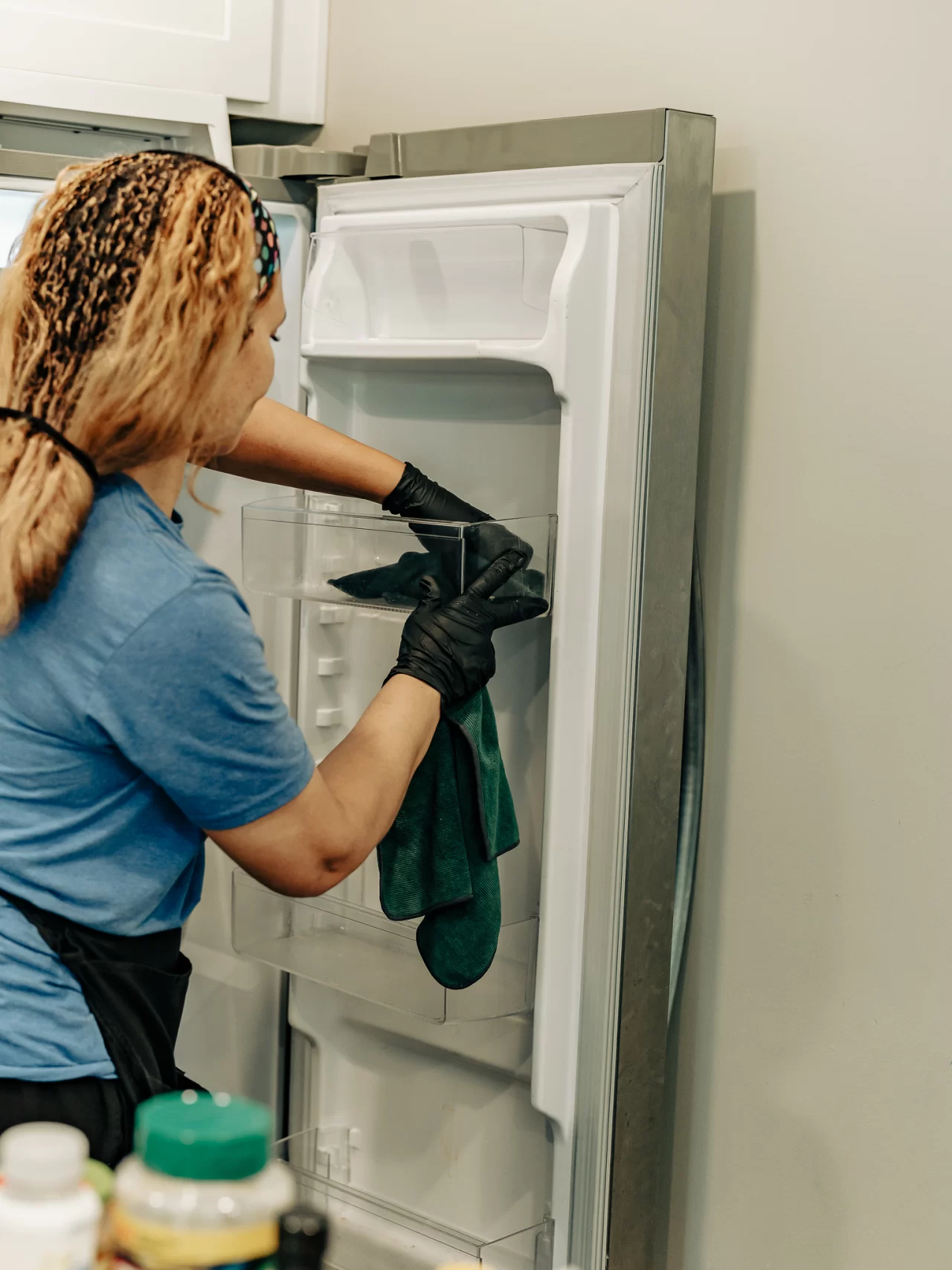 A Minit Maids team member carefully cleaning refrigerator shelves